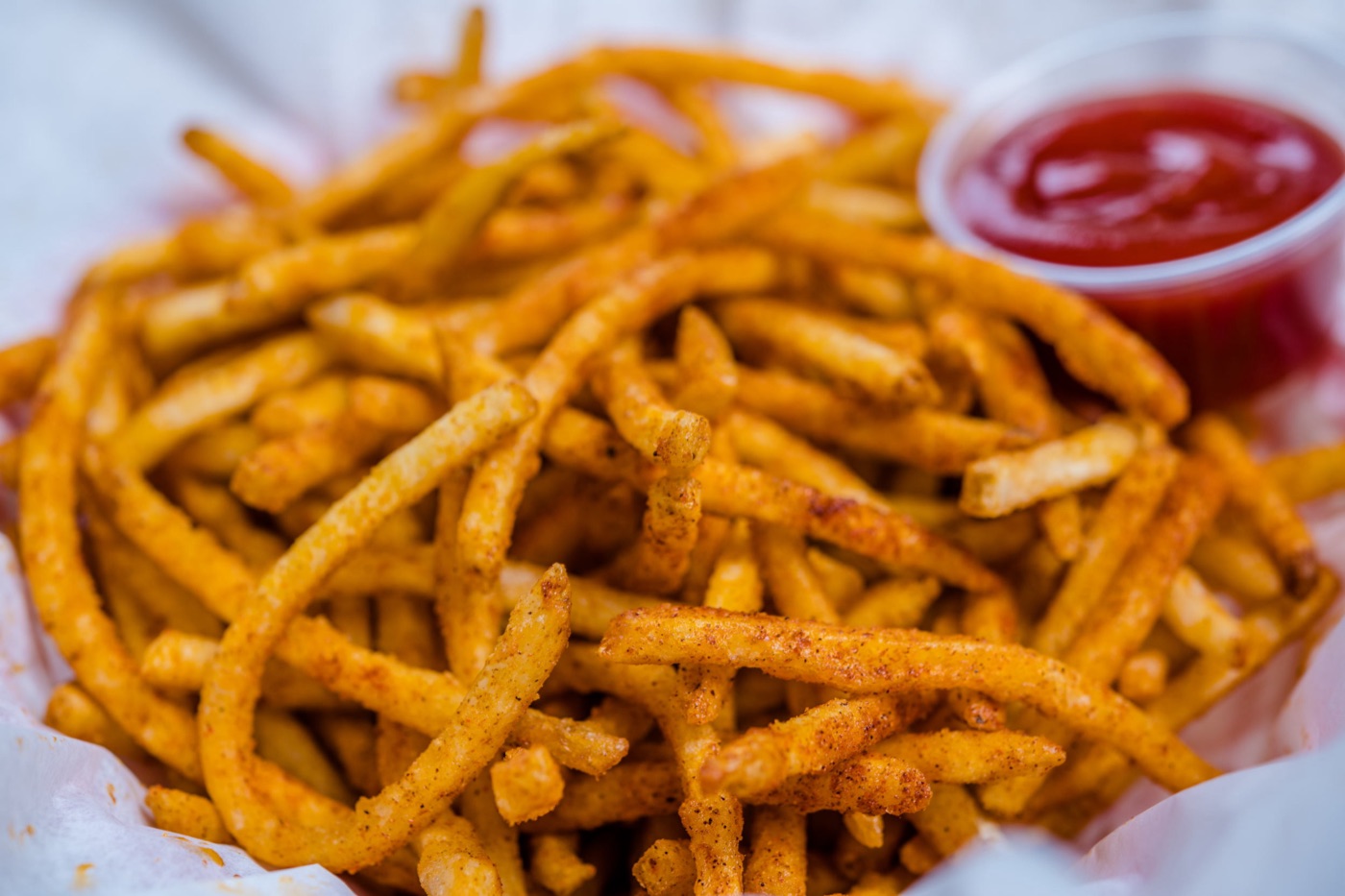 Cajun fries with a cup of ketchup.