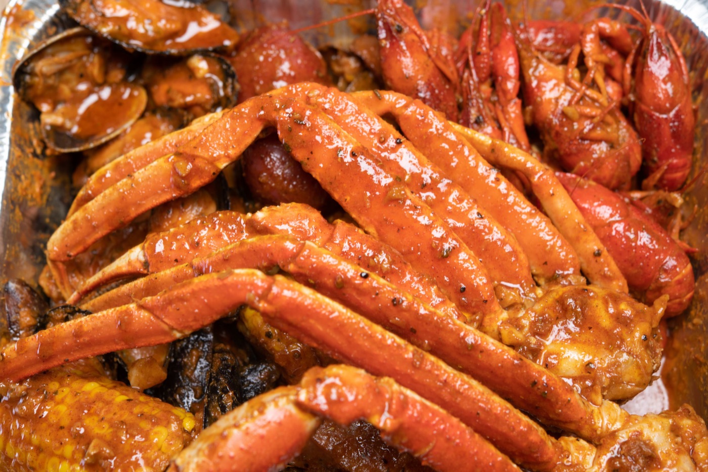 Snow crab legs, crawfish, clams and corn in Kickin&rsquo; Style sauce.